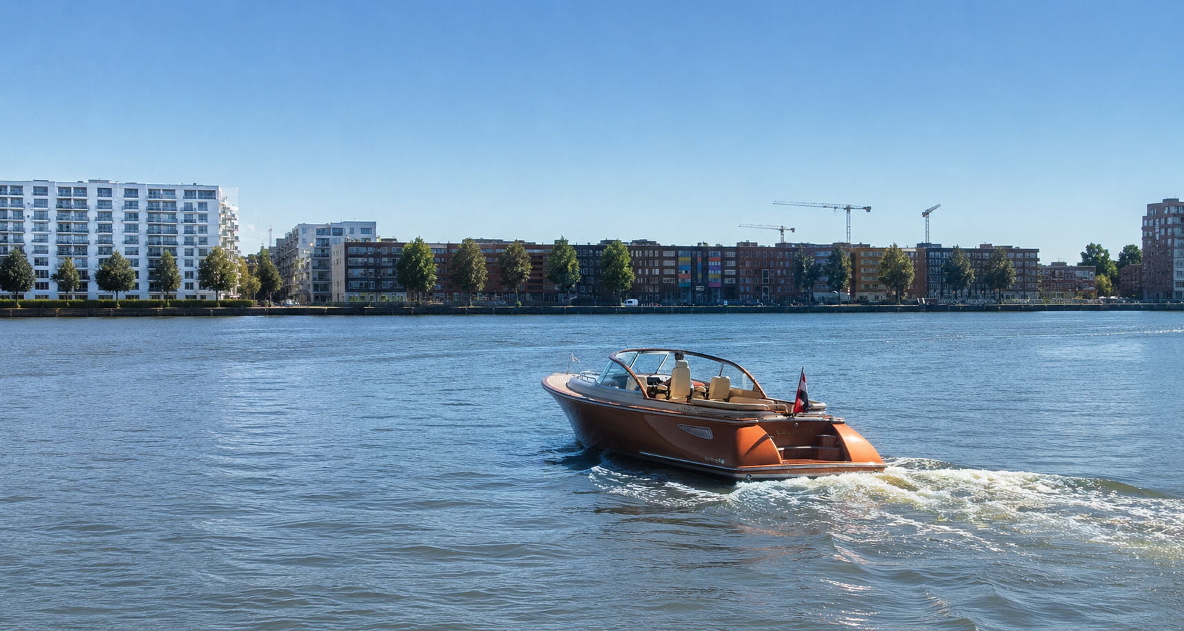 Wajer 37 vaart over het water met Amsterdamse gebouwen op de achtergrond